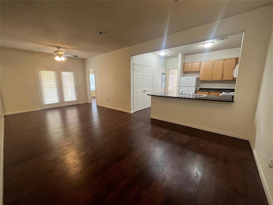 Unfurnished living room featuring a ceiling fan, dark wood-type flooring, and a textured ceiling