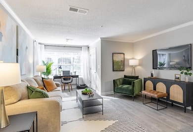 Living room with light hardwood / wood-style floors, a textured ceiling, and ornamental molding