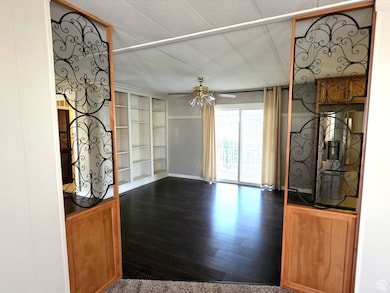 Unfurnished living room featuring dark wood-style flooring, a ceiling fan, and built in shelves