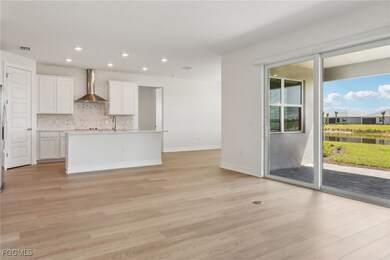 Kitchen featuring an island with sink, white cabinets, tasteful backsplash, light wood-type flooring, and recessed lighting