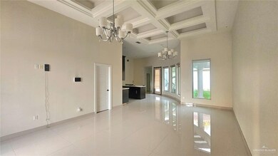 Unfurnished room with a towering ceiling, light tile patterned floors, coffered ceiling, beam ceiling, and a chandelier