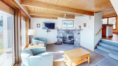 Living room with a fireplace, carpet, a wall mounted AC, a wooden ceiling with exposed beams, and stairs