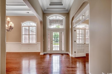 Entryway featuring ornamental molding, hardwood / wood-style flooring, a chandelier, and wainscoting