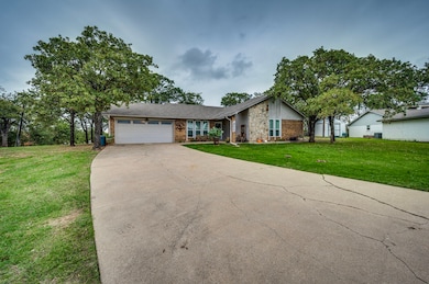 View of front of house featuring an attached garage, a front yard, concrete driveway, and brick siding
