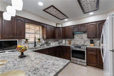Kitchen with stainless steel electric range oven, freestanding refrigerator, dark brown cabinets, light tile patterned floors, and decorative backsplash