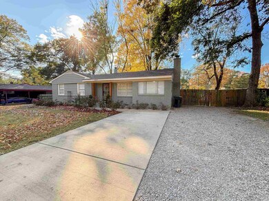 Ranch-style house with a chimney, brick siding, and driveway