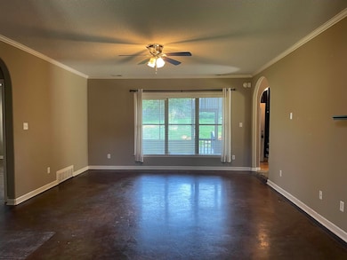 Greatroom room featuring arched walkways, finished concrete floors, a ceiling fan, ornamental molding, and a textured ceiling