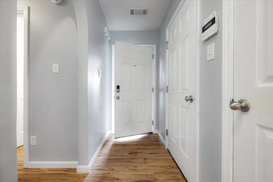 Hall with baseboards, light wood-style flooring, and arched walkways