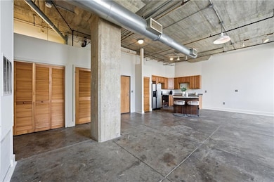 Garage with baseboards and stainless steel fridge with ice dispenser