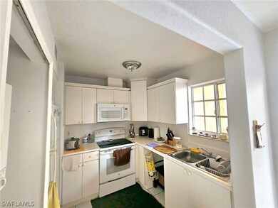 Kitchen featuring white appliances, sink, light ti