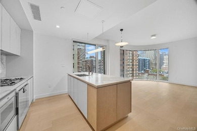 Kitchen featuring white cabinetry, pendant lighting, light stone countertops, light wood-type flooring, and modern cabinets