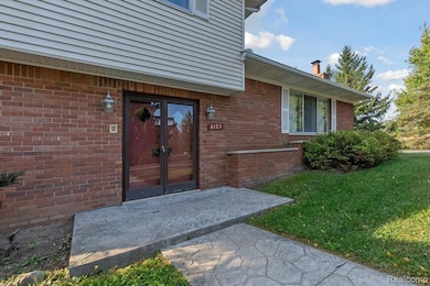 View of exterior entry featuring a patio area, brick siding, a lawn, a chimney, and french doors