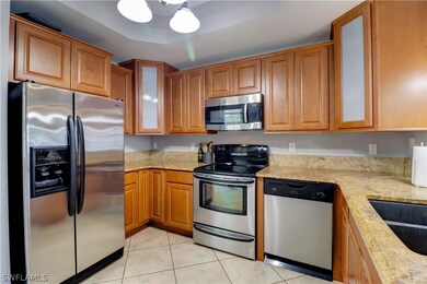 Kitchen with sink, light tile flooring, light stone counters, and stainless steel appliances