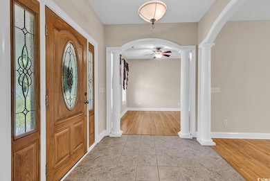 Foyer featuring decorative columns, arched walkways, ceiling fan, and baseboards