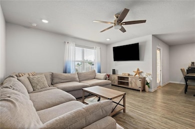 Living area featuring ceiling fan, wood finished floors, baseboards, a textured ceiling, and recessed lighting