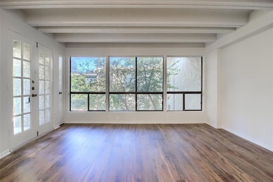 Empty room with beam ceiling, dark wood-type floo