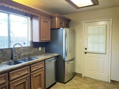 Deep stainless steel double-sink in well equipped kitchen.