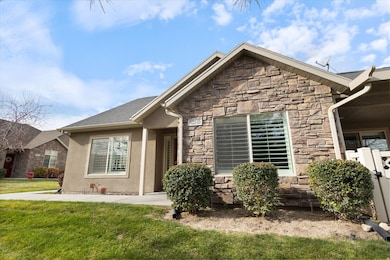View of front of property featuring stone siding, a front yard, and stucco siding