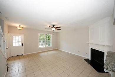 Unfurnished living room featuring plenty of natural light, a large fireplace, stairs, and ceiling fan