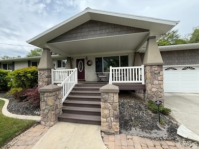 View of exterior entry featuring a porch, an attached garage, and driveway