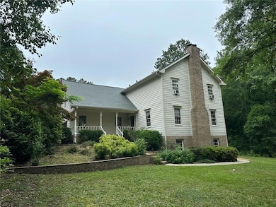 View of side of home featuring a chimney, a yard, and covered porch