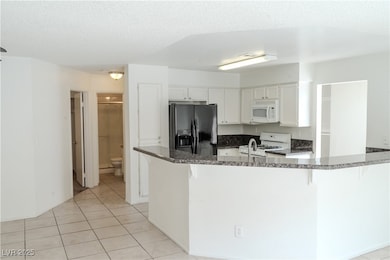 Kitchen with white appliances, a peninsula, a text