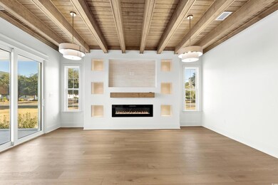 Unfurnished living room featuring beam ceiling, wo