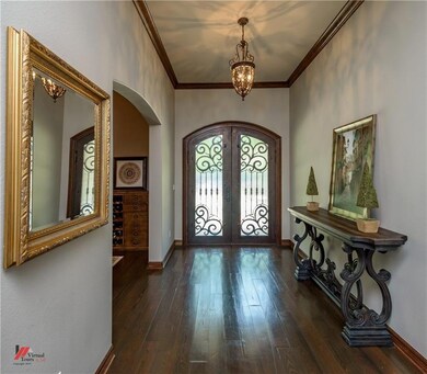 Double arched iron front doors open to expansive e