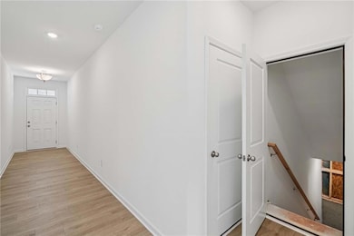 Hallway with light wood-style flooring, an upstairs landing, and recessed lighting