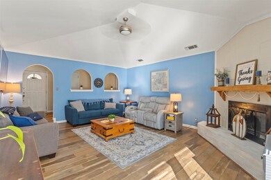 Living room featuring vaulted ceiling, arched walkways, a fireplace, wood-type flooring, and ornamental molding