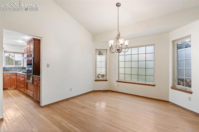 Unfurnished dining area with light wood finished floors, a chandelier, and lofted ceiling