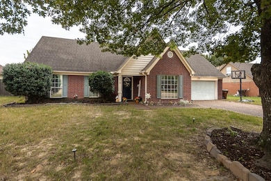 View of front of property with brick siding, roof with shingles, a front yard, and driveway