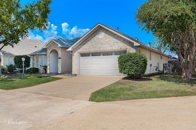 Ranch-style home with a front yard, concrete driveway, brick siding, and an attached garage