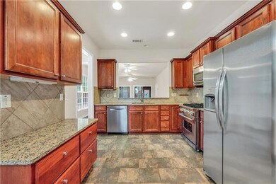 Kitchen featuring a sink, light stone counters, ceiling fan, visible vents, and appliances with stainless steel finishes