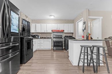 Kitchen with freestanding refrigerator, stainless steel stove, dark countertops, washer / clothes dryer, and a kitchen breakfast bar