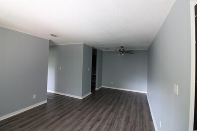 Unfurnished room with a textured ceiling, dark wood-style floors, and ceiling fan