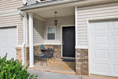View of exterior entry with a porch, a garage, and stone siding