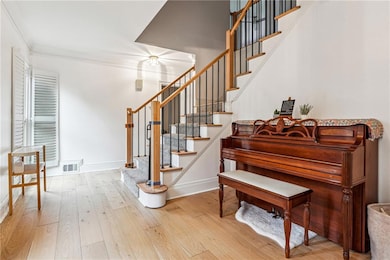 Stairway with wood finished floors, crown molding,