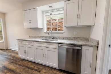 Kitchen with a sink, white cabinetry, light stone 