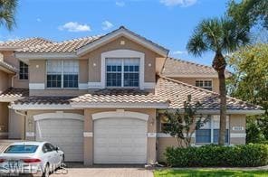 View of front of home featuring driveway, a tile roof, and stucco siding