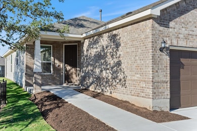 View of exterior entry with brick siding, roof wi