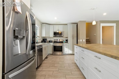 Kitchen with sink, decorative light fixtures, appliances with stainless steel finishes, decorative backsplash, and white cabinets