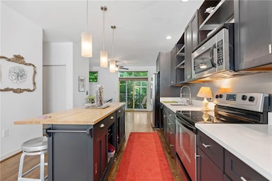 Kitchen with appliances with stainless steel finishes, wooden counters, open shelves, a center island, and a breakfast bar