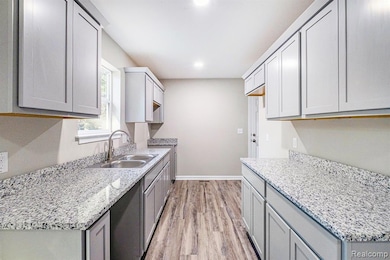 Kitchen featuring gray cabinets, light wood finished floors, light stone countertops, and recessed lighting