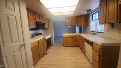Kitchen featuring white appliances, light wood fin
