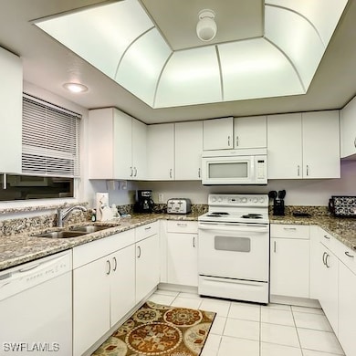 Kitchen with white appliances, white cabinets, lig