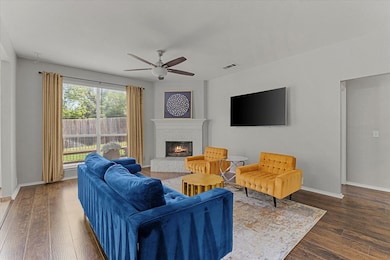 Living room featuring a glass covered fireplace, ceiling fan, and wood finished floors