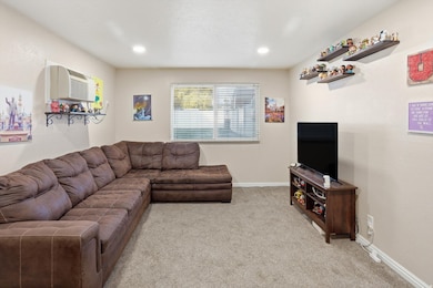 Living room with light colored carpet, an AC wall unit, and recessed lighting