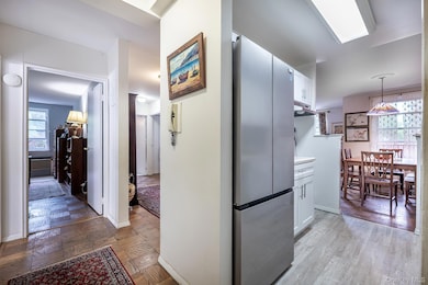 Kitchen featuring freestanding refrigerator, white cabinets, under cabinet range hood, decorative light fixtures, and light countertops