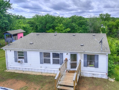 View of front of house featuring roof with shingles, cooling unit, and a forest view